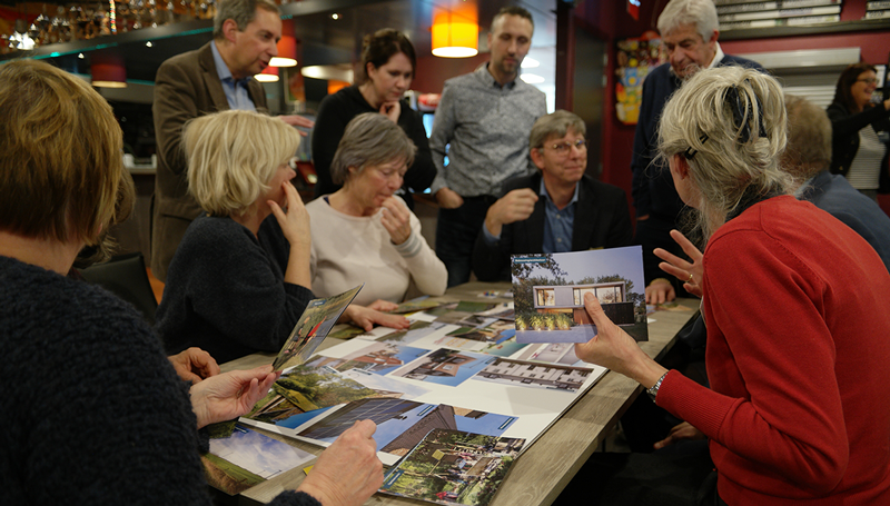 Mensen rond een tafel met geprinte foto's op een participatiebijeenkomst
