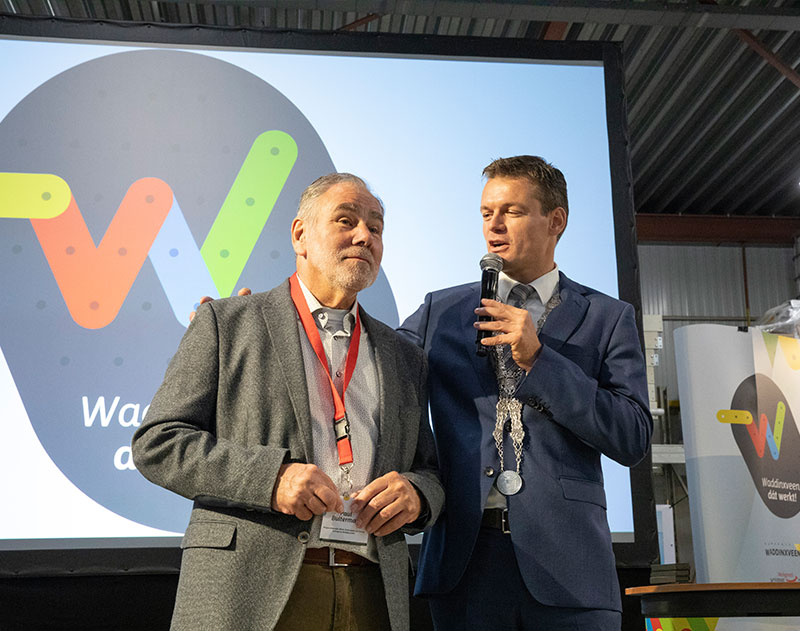 Burgemeester Evert Jan Nieuwenhuis op het podium met een andere man voor Waddinxveen, dát werkt