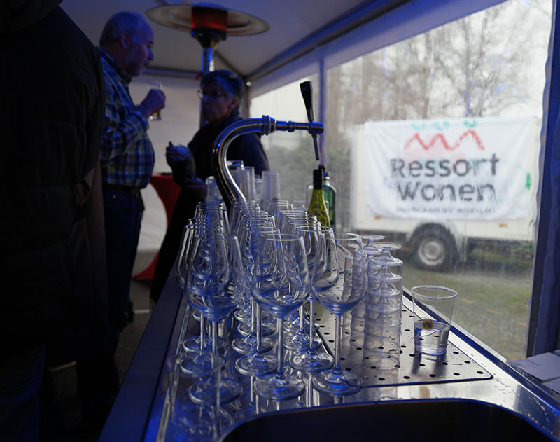 Bar met glazen met een aanhanger van Ressort Wonen op de achtergrond
