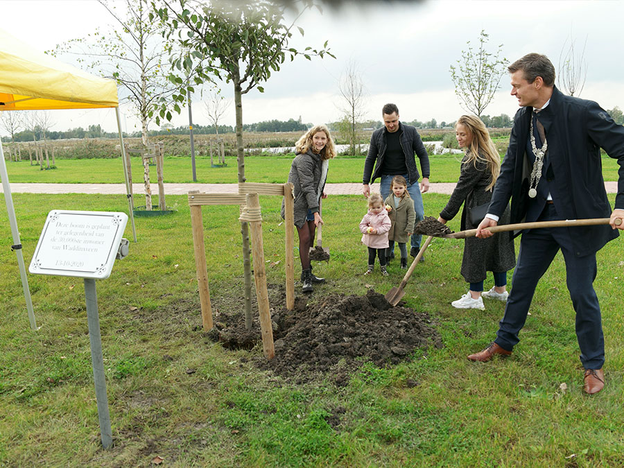Burgemeester Evert Jan Nieuwenhuis die ter ere van en samen met de 30.000ste inwoner van Waddinxveen een boom plant